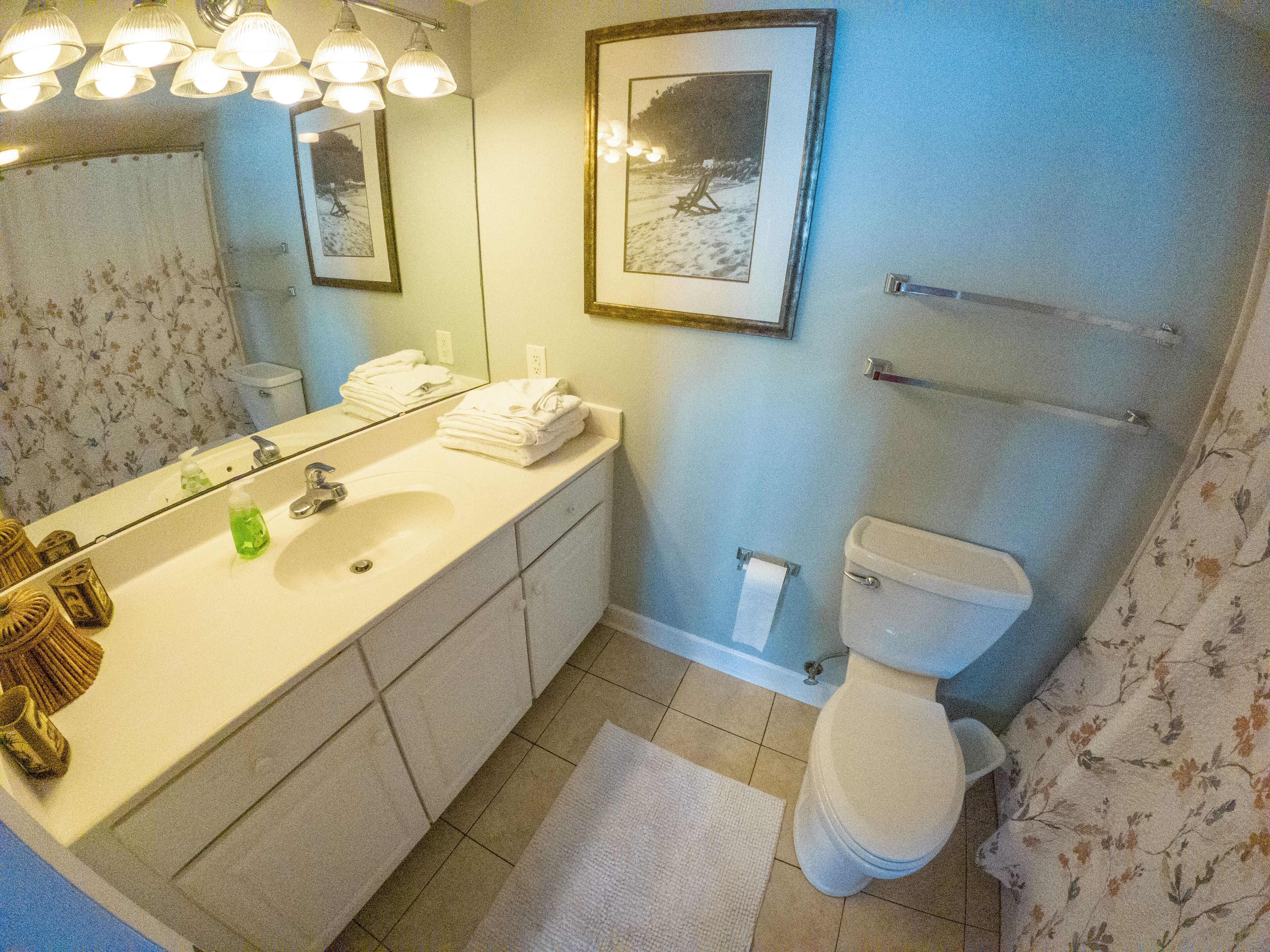 A bathroom with a sink, mirror, toilet, and towel rack.