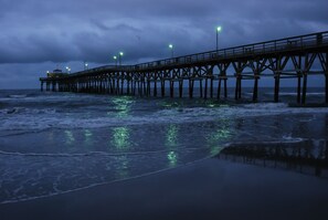 A pier extending into the water with lights along its length.
