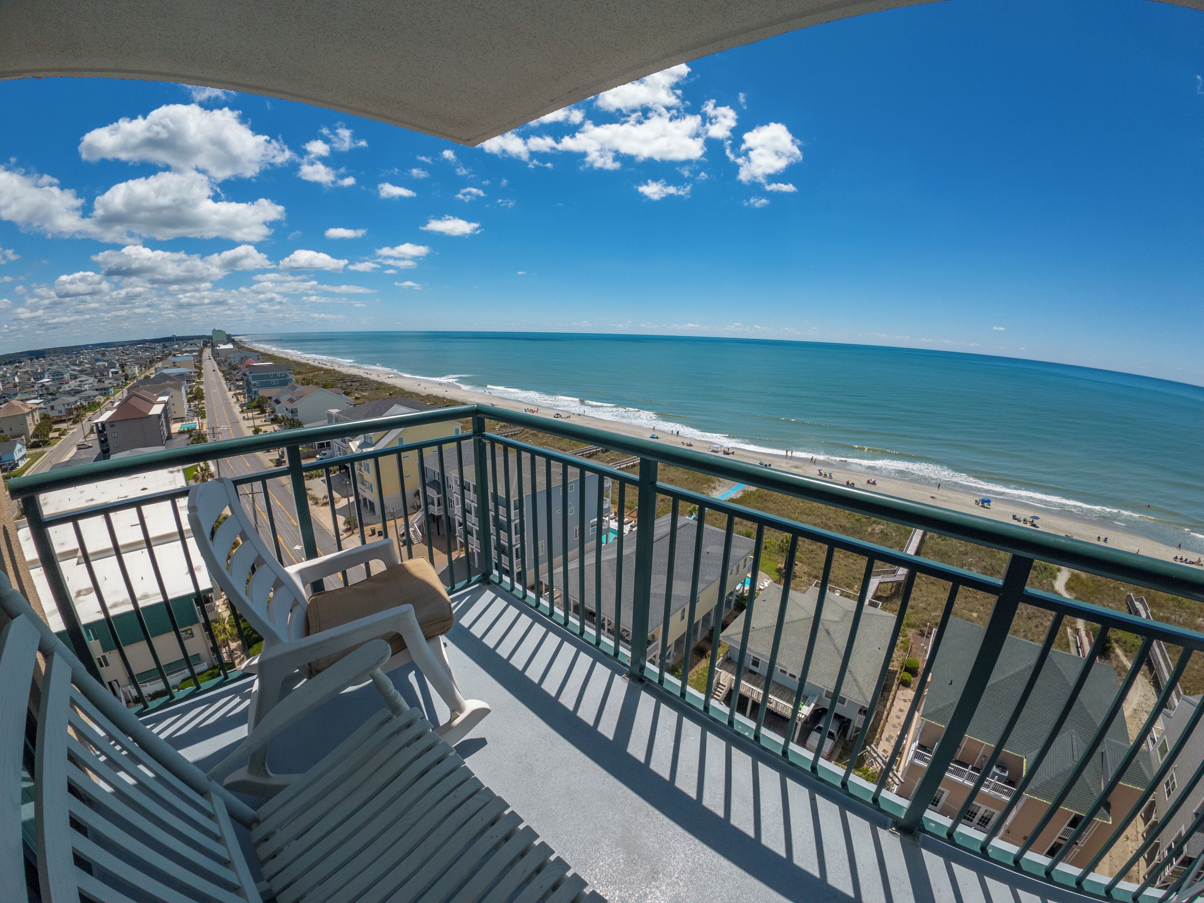 A balcony with a view of the beach and ocean.