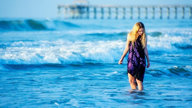 Une personne se tient dans l’océan, au milieu des vagues.