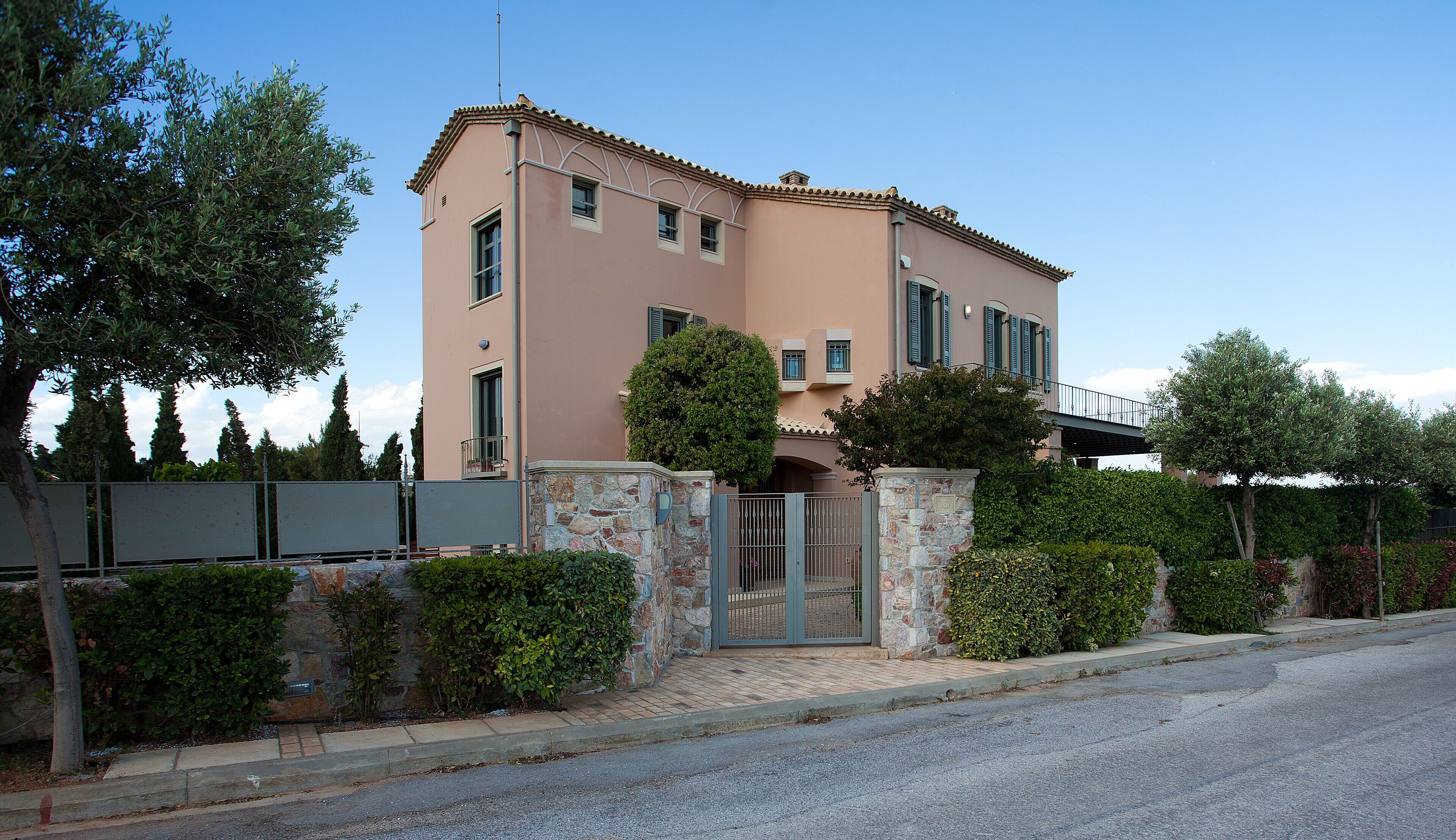 A two-story building with a stone facade, a gated entrance, and a small balcony.