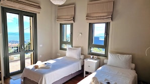 A hotel room with two beds, large windows, and a view of the sea.