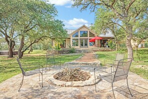 A patio area with stone flooring, metal chairs, and a fire pit.