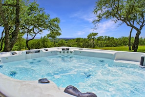 Un jacuzzi rodeado de árboles con un cielo despejado al fondo.