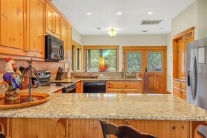 Una cocina con armarios de madera, encimeras de granito, electrodomésticos de acero inoxidable y un gallo decorativo.