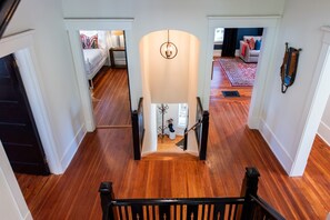 A staircase leading to a bedroom with a bed, a chandelier, and a view of another room with a couch. - 6BR/5 Bath|Hot Tub|Parking|2 Kitchens/Living Rooms (Louisville)