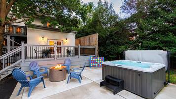 An outdoor patio area with a hot tub, fire pit, and seating.
