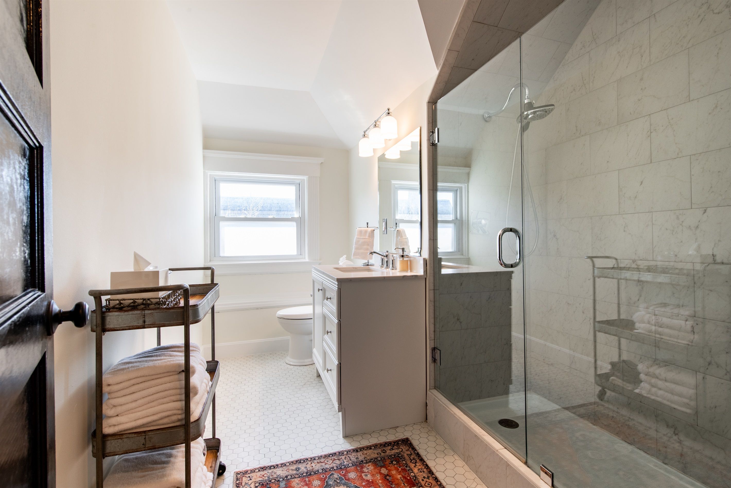 A modern bathroom with a glass-enclosed shower, a white toilet, and a vanity with a mirror.