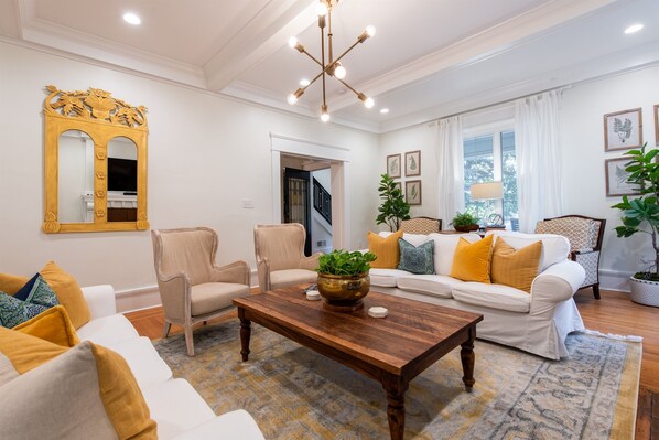 A living room with a wooden coffee table, white sofas, and a large mirror. - 6BR/5 Bath|Hot Tub|Parking|2 Kitchens/Living Rooms (Louisville)