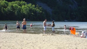 A beach with people swimming and standing in the water, a sandy shore, and a forested hillside in the background. - (3) BEAUTIFUL SUMMER RENTAL Nr ACADIA NATIONAL PARK & BAR HARBOR! 3 (Southwest Harbor)