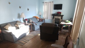 Un salon comprenant un canapé, un fauteuil, une table basse en bois et une cheminée.