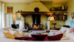 Una sala de estar acogedora con chimenea, un sofá, una mesa de centro y una estantería llena de libros.