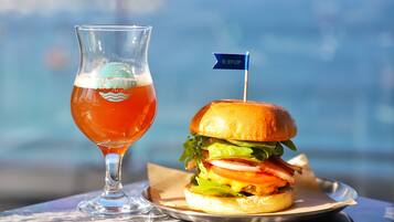 Una cerveza con una bandera sobre una mesa, junto a una hamburguesa.