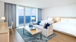 A hotel room with a large bed, a sofa, a desk, and a view of the ocean. - Lotte Resort Sokcho (Sokcho)