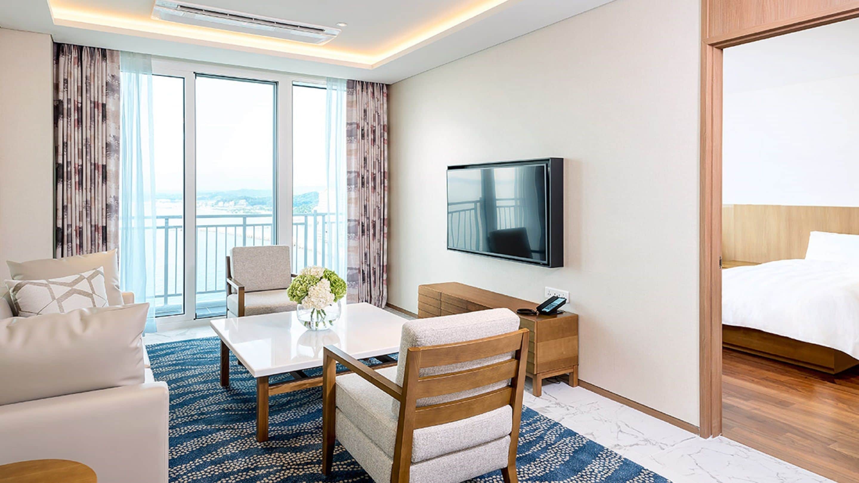 A hotel room with a bed, a TV, a desk, a chair, and a sofa.