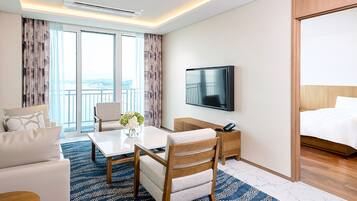 A hotel room with a bed, a TV, a desk, a chair, and a sofa.
