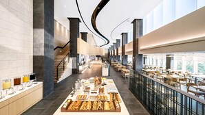 A modern hotel lobby with a central food display, seating areas, and a staircase. - Lotte Resort Sokcho (Sokcho)