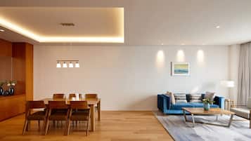 Een moderne woonkamer met een eethoek, met een houten eettafel, stoelen, een blauwe bank en een salontafel.