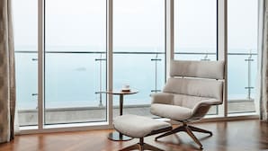 A modern room with a large window, a cushioned chair, a small table, and a view of the sea. - Lotte Resort Sokcho (Sokcho)