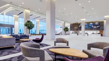 Un vestíbulo amplio con muebles modernos, ventanas grandes y una zona de recepción.