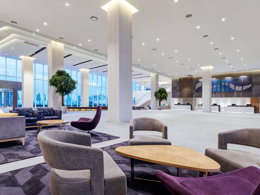 Un vestíbulo amplio con muebles modernos, ventanas grandes y una zona de recepción.