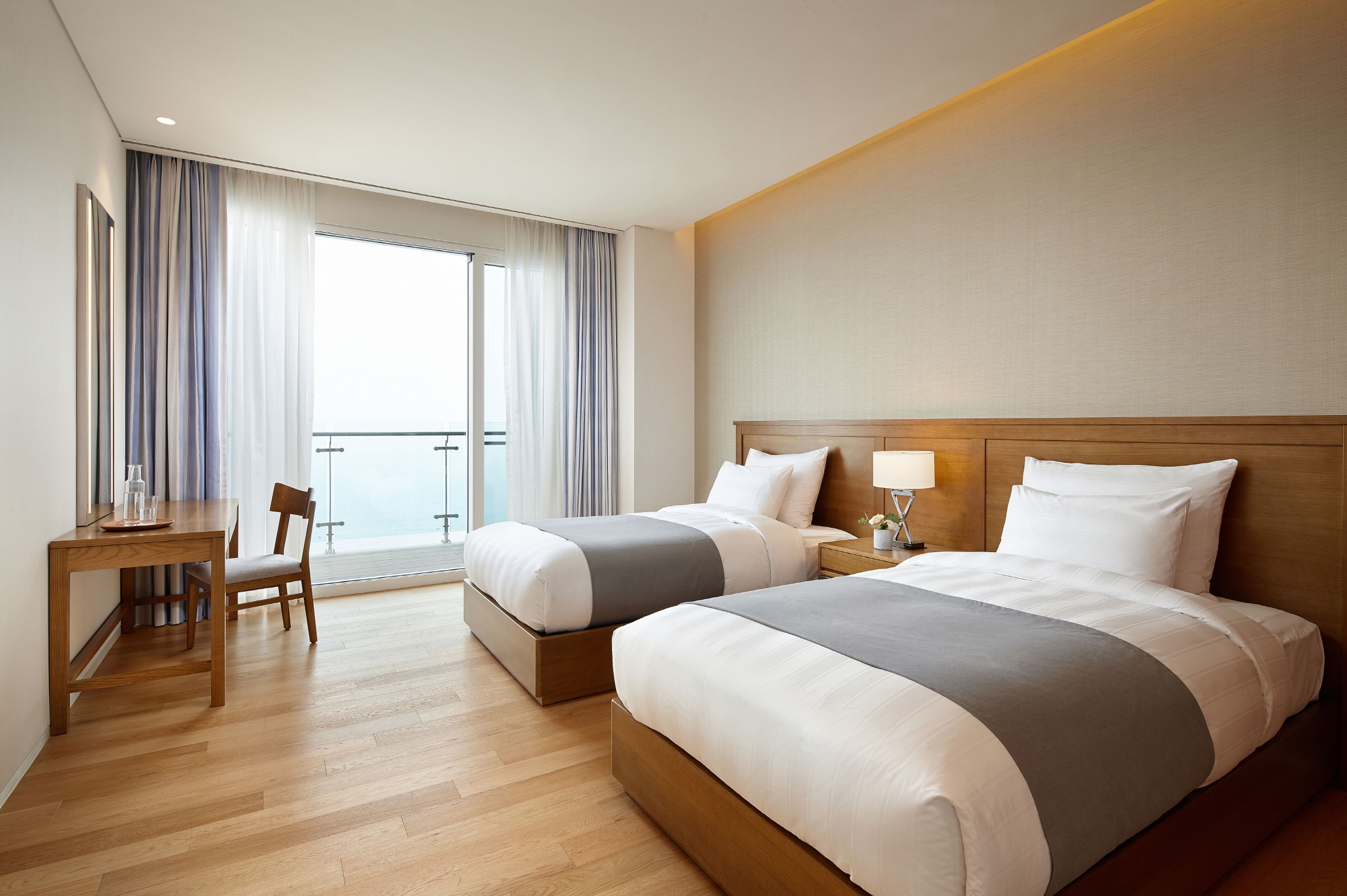 A hotel room with two beds, a desk, and a chair.