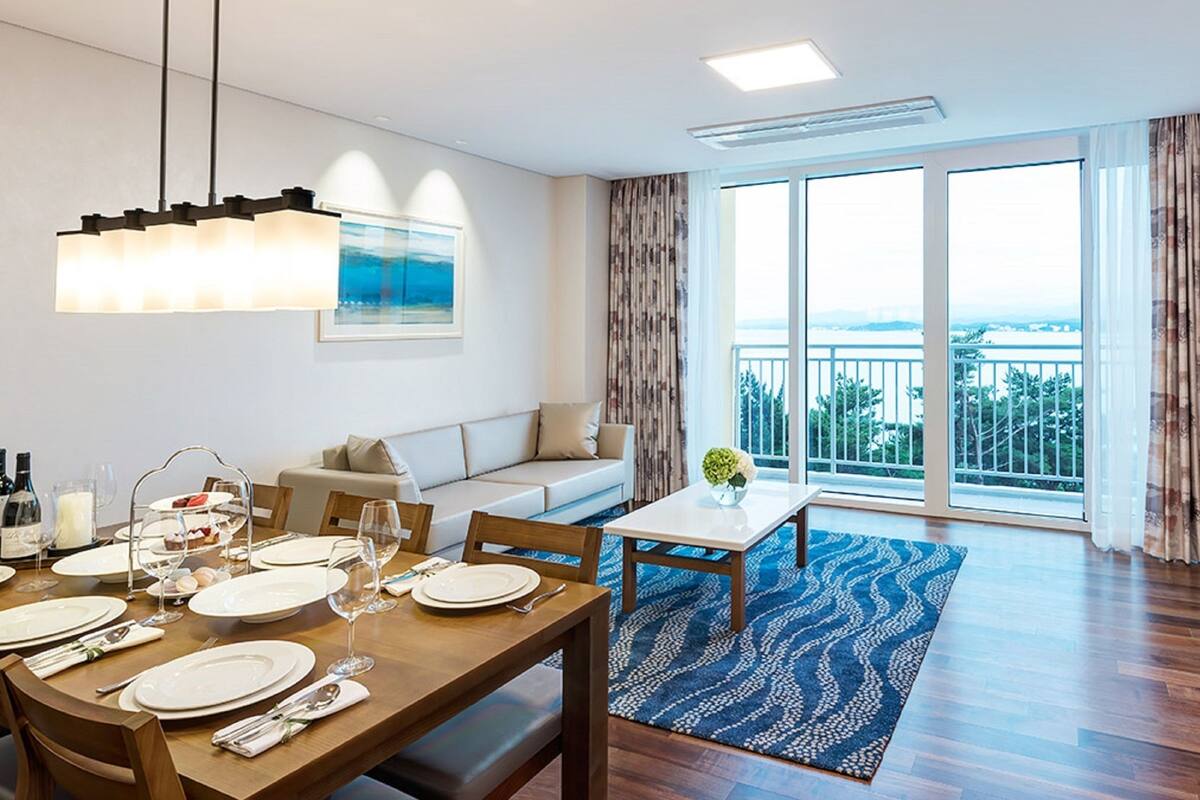 Un salon moderne avec un coin repas, de grandes fenêtres et un balcon offrant une vue dégagée.