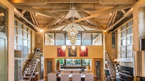 A spacious interior with high ceilings, wooden beams, and large windows.