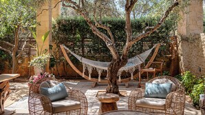 A patio with wicker furniture, a hammock, and a tree.