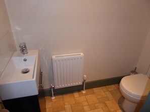 Un baño con lavamanos blanco, inodoro y radiador.