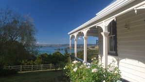 A white house with a porch overlooking a lake. - Kauri Villas (Parua Bay)