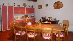 Een eetruimte met een houten tafel en stoelen, rode kasten en een plafond met zichtbare balken.