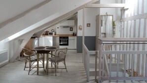 Een moderne keuken met witte kasten, een houten eettafel en rieten stoelen.