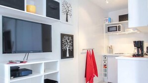 A modern kitchen with white cabinetry, a flat-screen TV, and a microwave. - Air-conditioned studio with a garage near the Port of Nice (Nice)