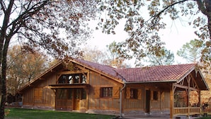 A rustic wooden cabin with a tiled roof, a porch, and a stone foundation. - LA LANDAISE DU CHARPENTIER <br>17 Chemin Traouquevert <br>40430 CALLEN  (Callen)