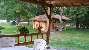 An outdoor patio with a wooden pergola, a table with chairs, and potted plants. - LA LANDAISE DU CHARPENTIER <br>17 Chemin Traouquevert <br>40430 CALLEN  (Callen)