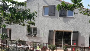 A house with a white exterior, a balcony with metal railings, and potted plants.