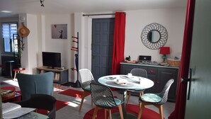 Un salon chaleureux avec une table ronde, des chaises, un téléviseur et une bibliothèque.
