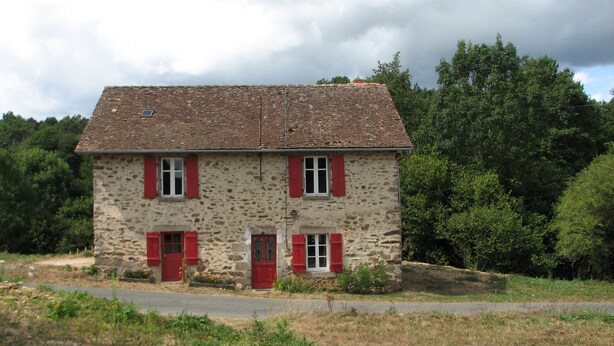 A two-story stone house with red shutters and a tiled roof, surrounded by greenery. - Cottage in the heart of the Périgord-Limousin Regional Nature Park (Dournazac)