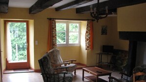 A living room with a fireplace, two armchairs, a coffee table, and a television. - Cottage in the heart of the Périgord-Limousin Regional Nature Park (Dournazac)