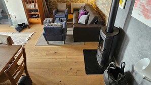 A cozy living room with a stone wall, a fireplace, and a wooden ceiling.