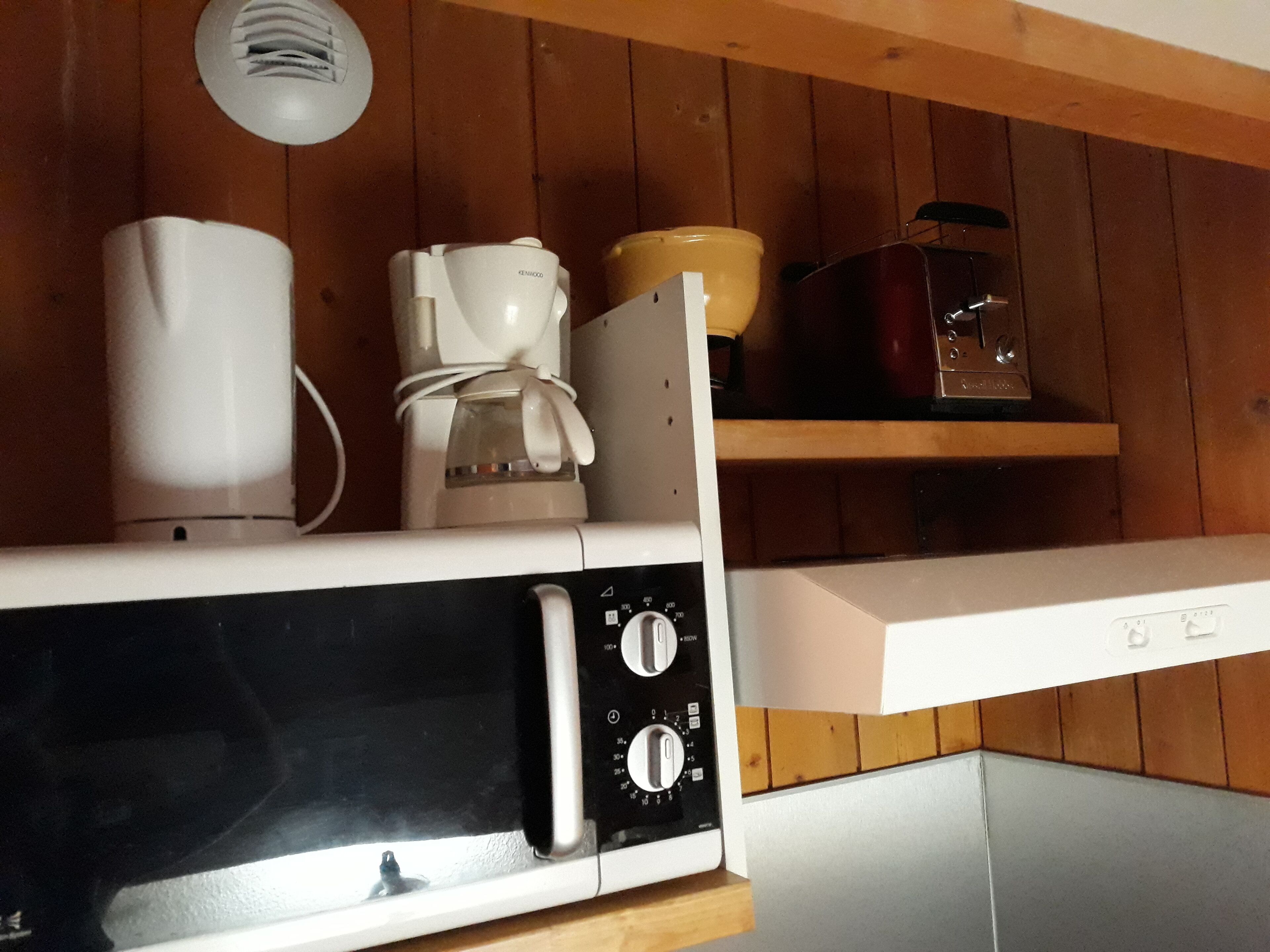 Eine Küche mit Mikrowelle, Kaffeemaschine und Toaster auf der Arbeitsfläche.