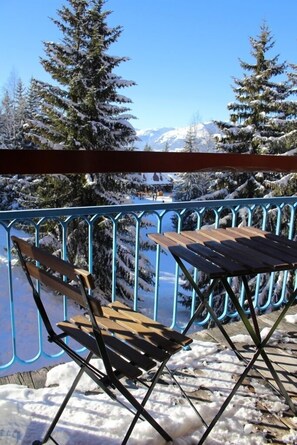 A balcony with a metal railing, a wooden table, and a wooden chair. - 4-star apartment ♥ Ski-in ski-out ♥ Very comfortable - Station Arcs 1800 (Bourg-Saint-Maurice)