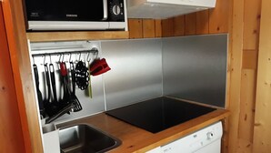 Una cocina compacta equipada con microondas, estufa, lavaplatos y pileta.