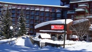 Un hotel con un paisaje nevado, un cartel de un club y un edificio con varios balcones.