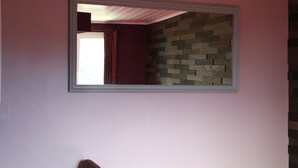 A room with a mirror on the wall, a patterned wall, and a door with a curtain.