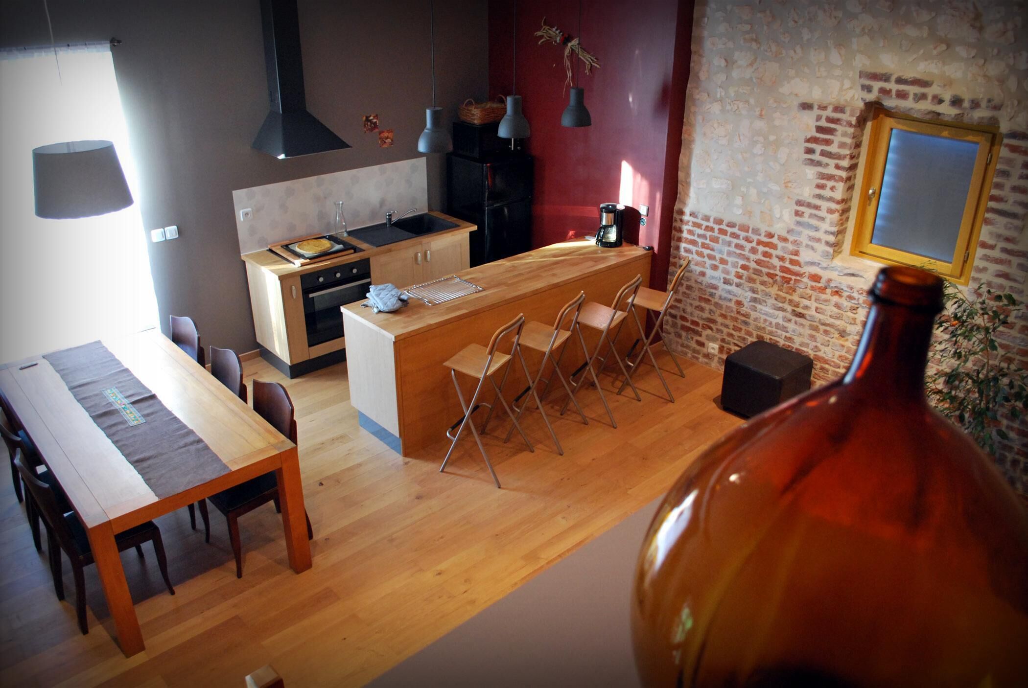 Une cuisine moderne avec un îlot central en bois, des tabourets de bar et une grande fenêtre.