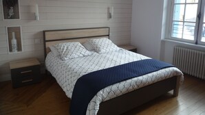 Una camera da letto con un letto in legno, pareti bianche e una finestra.