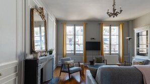Una habitación con chimenea, un espejo grande, un sofá, una silla y una televisión.