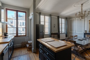 Una cocina amplia con una isla grande, suelo de madera y vistas a la ciudad a través de amplias ventanas.